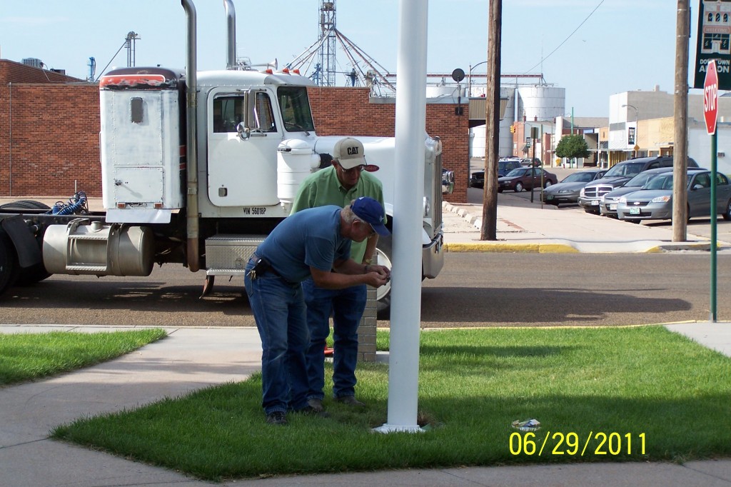 men attaching fittings to base of flagpole